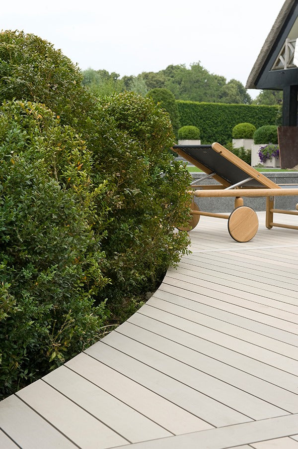 A soft rounded corner of Esthec decking surrounding shrubbery and vegetation.