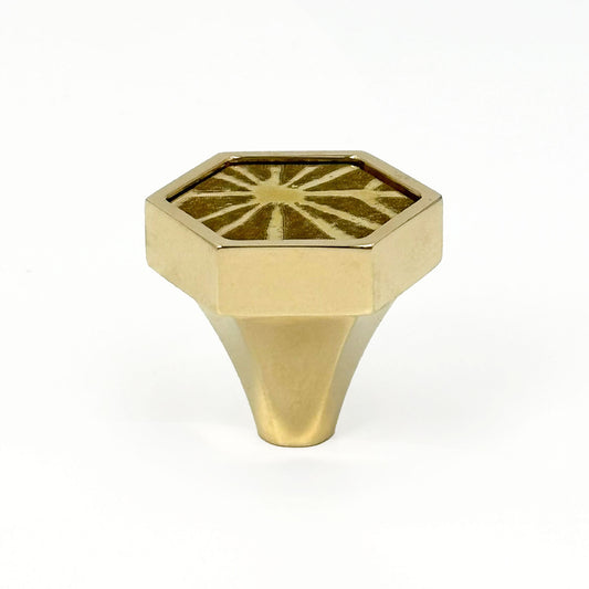 Hexagonal brass knob with etched sunburst design on a white background