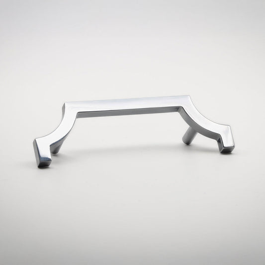 A modern polished chrome cabinet pull handle with a curved, geometric design, shown on a neutral light gray background.