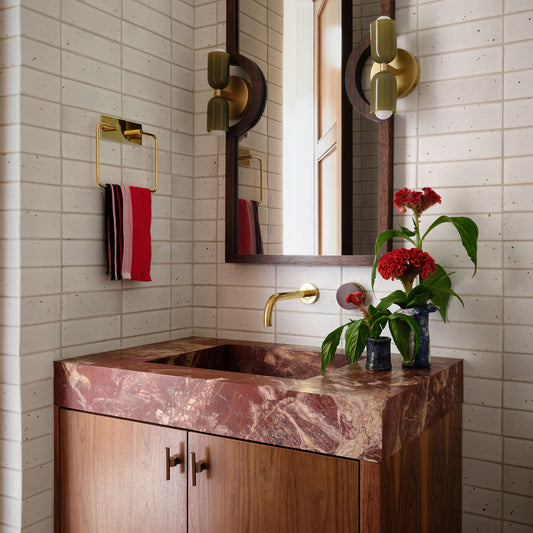 a bathroom sink with integrated marble top, wall-mounted faucet, and wood cabinetry with t-pull cabinet hardware