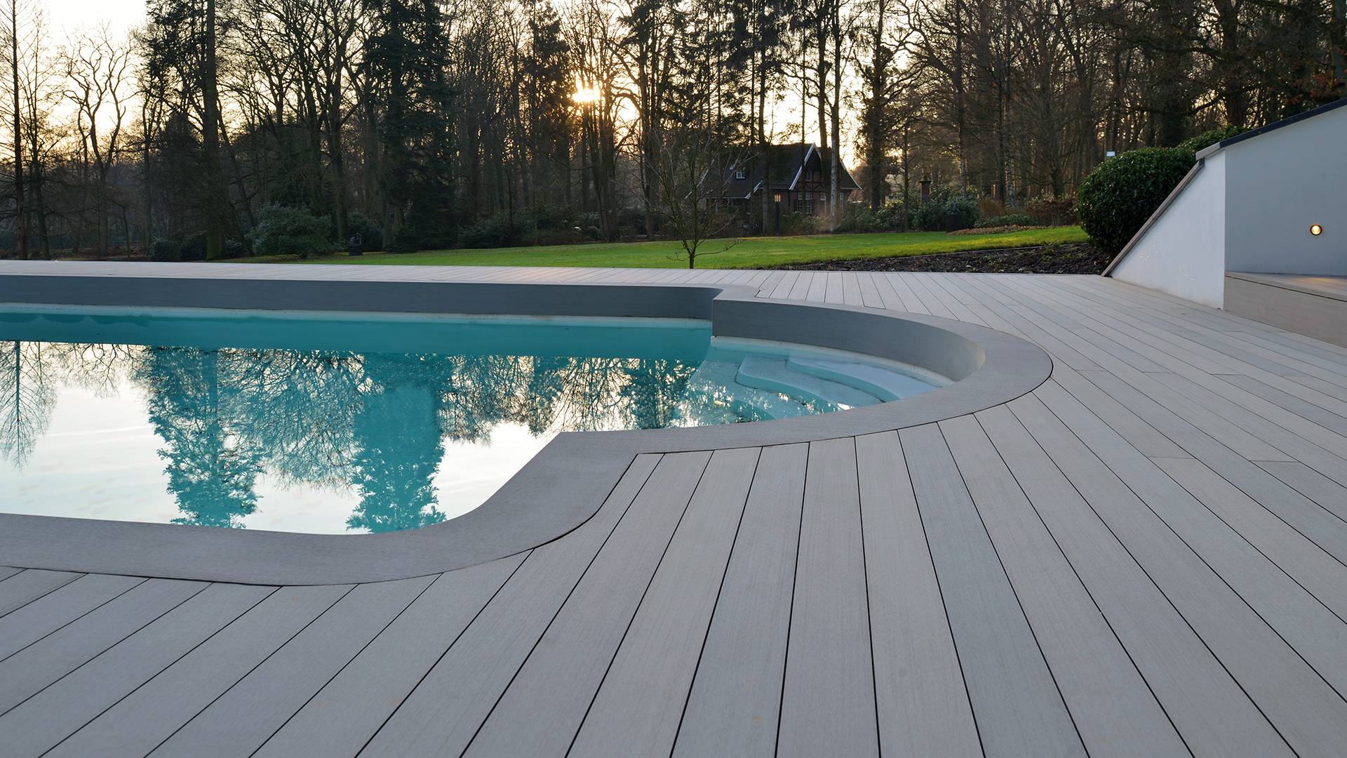 Esthec outdoor decking around a cartouche shaped pool surrounded by a vast green lawn