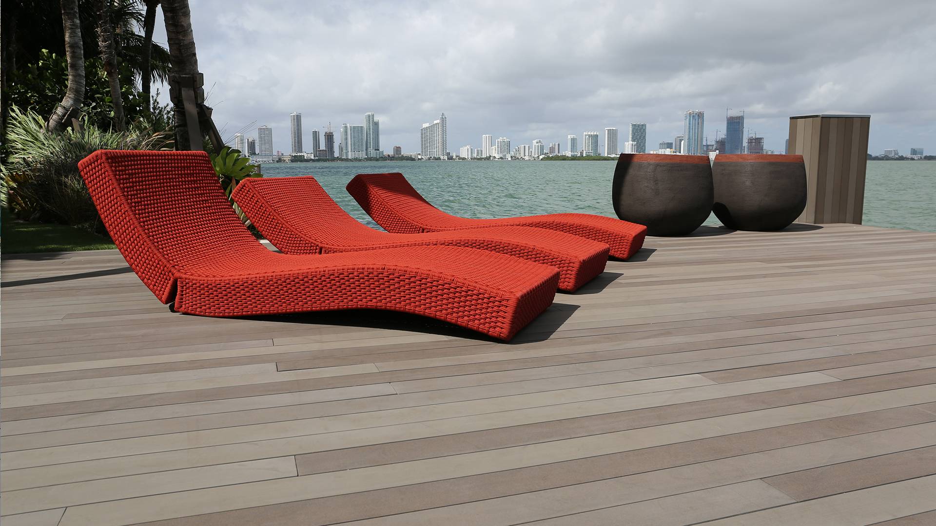 Three red rope beach loungers sitting on Esthec decking on a pier.