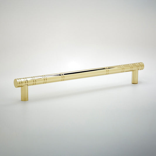 A polished brass cabinet pull handle with a decorative segmented rod design and cylindrical end caps, shown on a light gray gradient background.