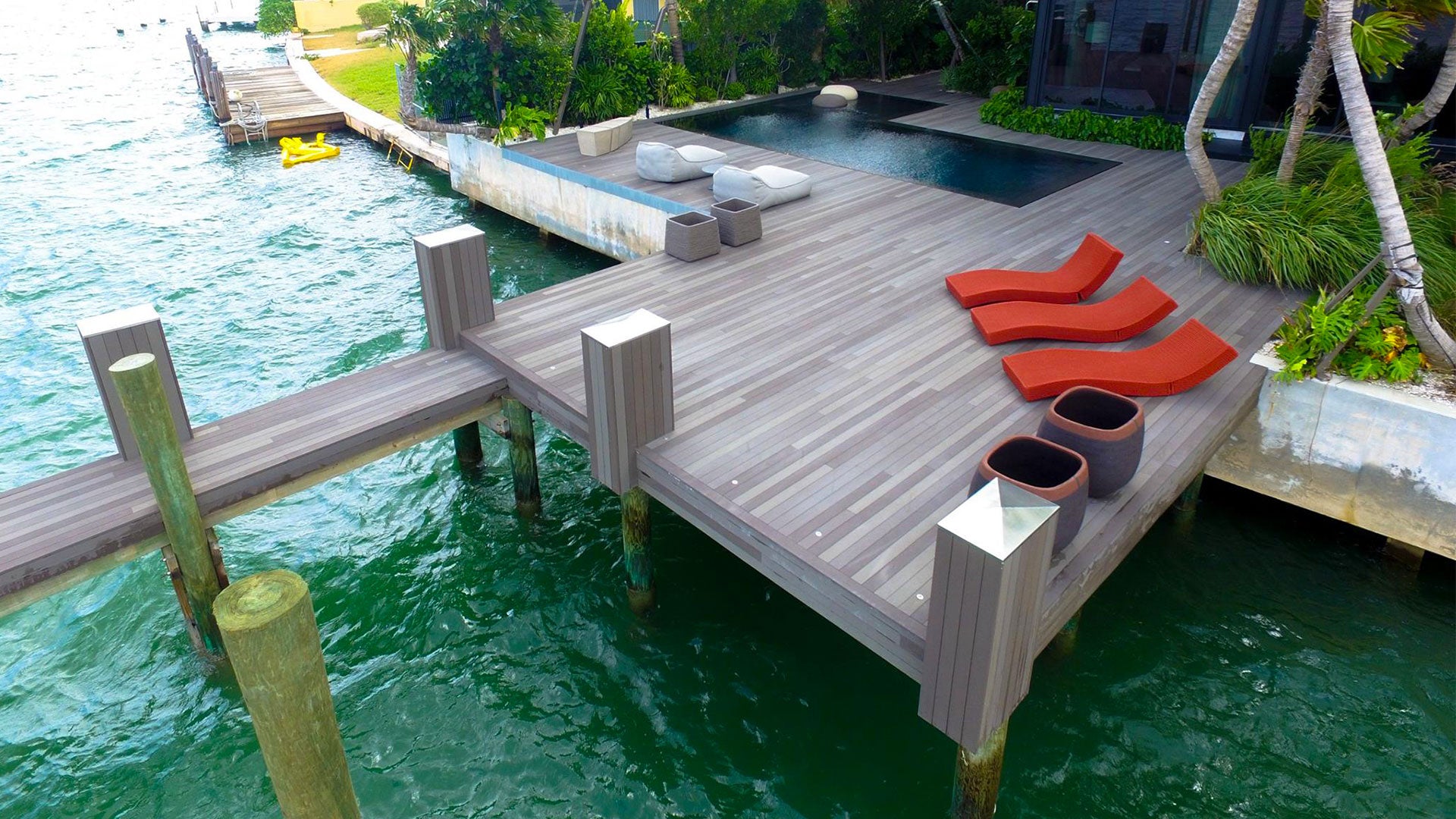 Three red rope beach loungers sitting on Esthec decking on a contemporary pier.