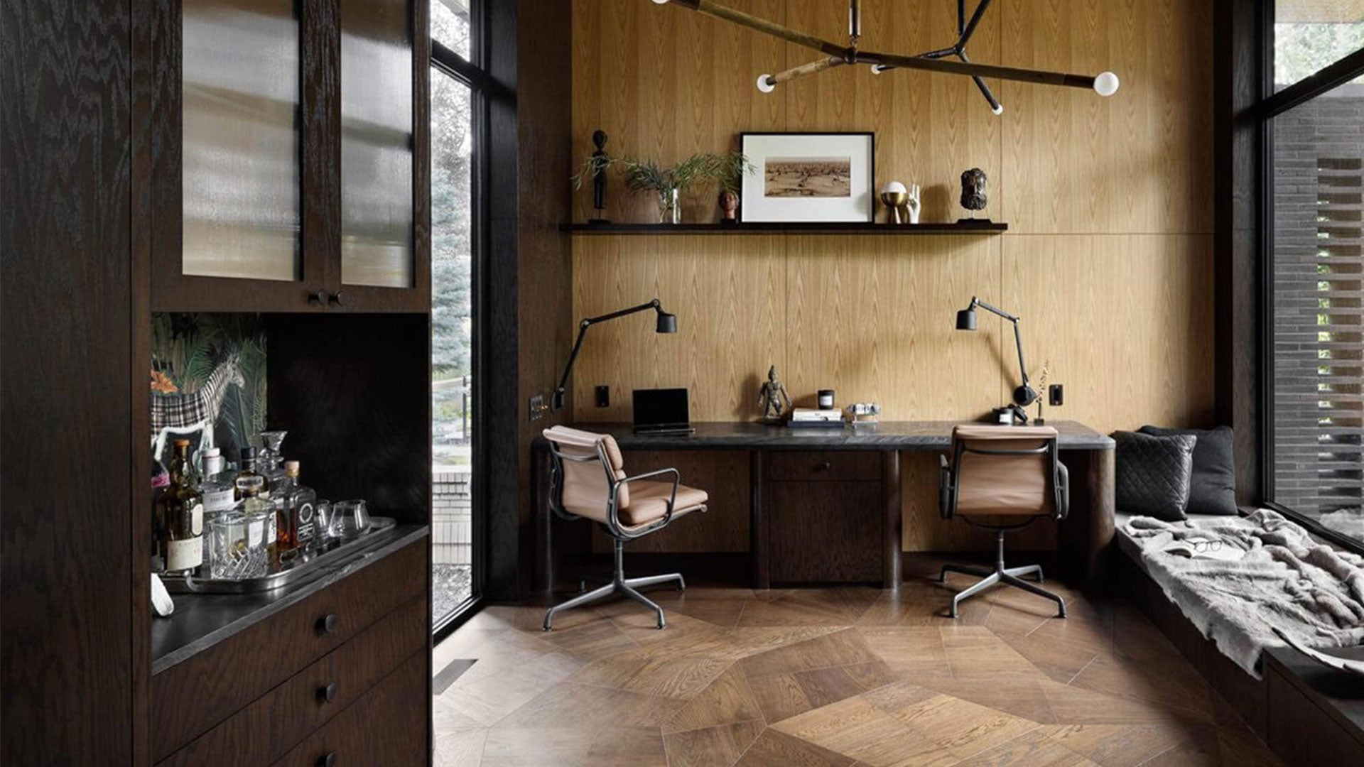 a double seated desk against a wall with modern task chairs atop an abstracted design wood parquet floor
