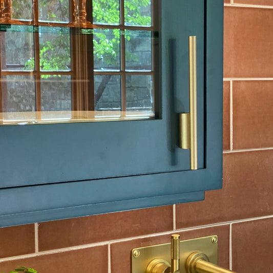 Counteralance Asymmetrical Cabinet Pull in Satin Brass installed on a colorful cabinet door