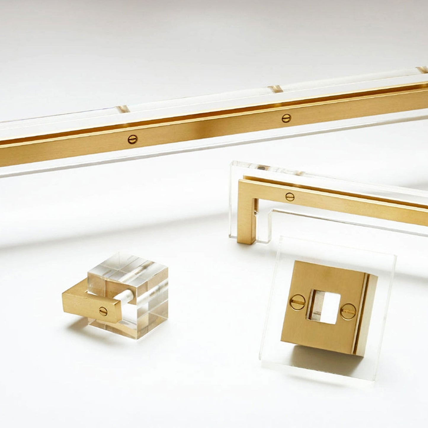 Gold-finished hardware components and clear acrylic blocks arranged on a clean white studio background.