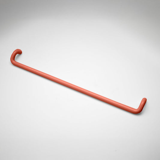 A minimalist coral metal cabinet pull with a curved, modern design, shown on a clean light gray background.