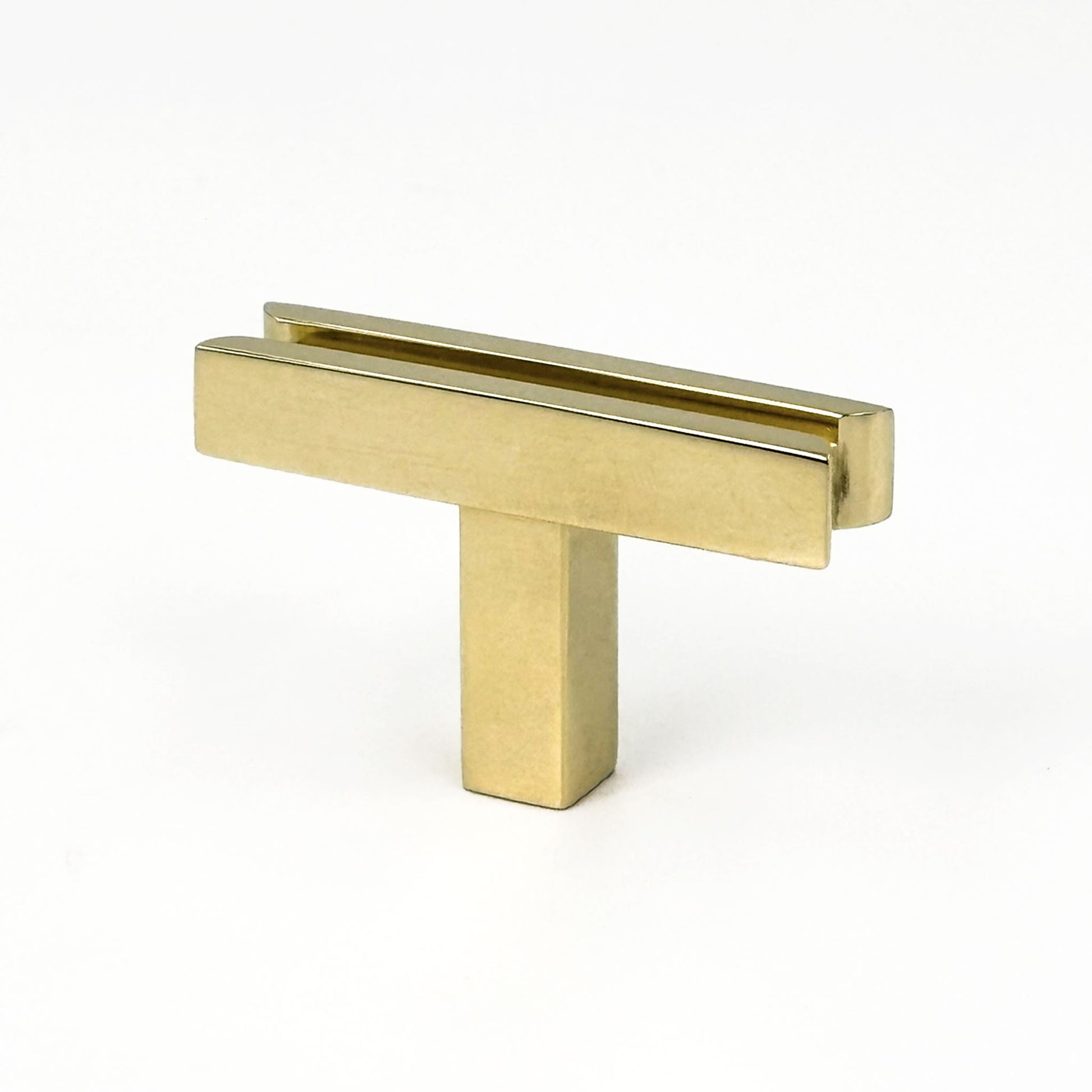 Angeled view of unlacquered brass cabinet T-pull handle on a white background