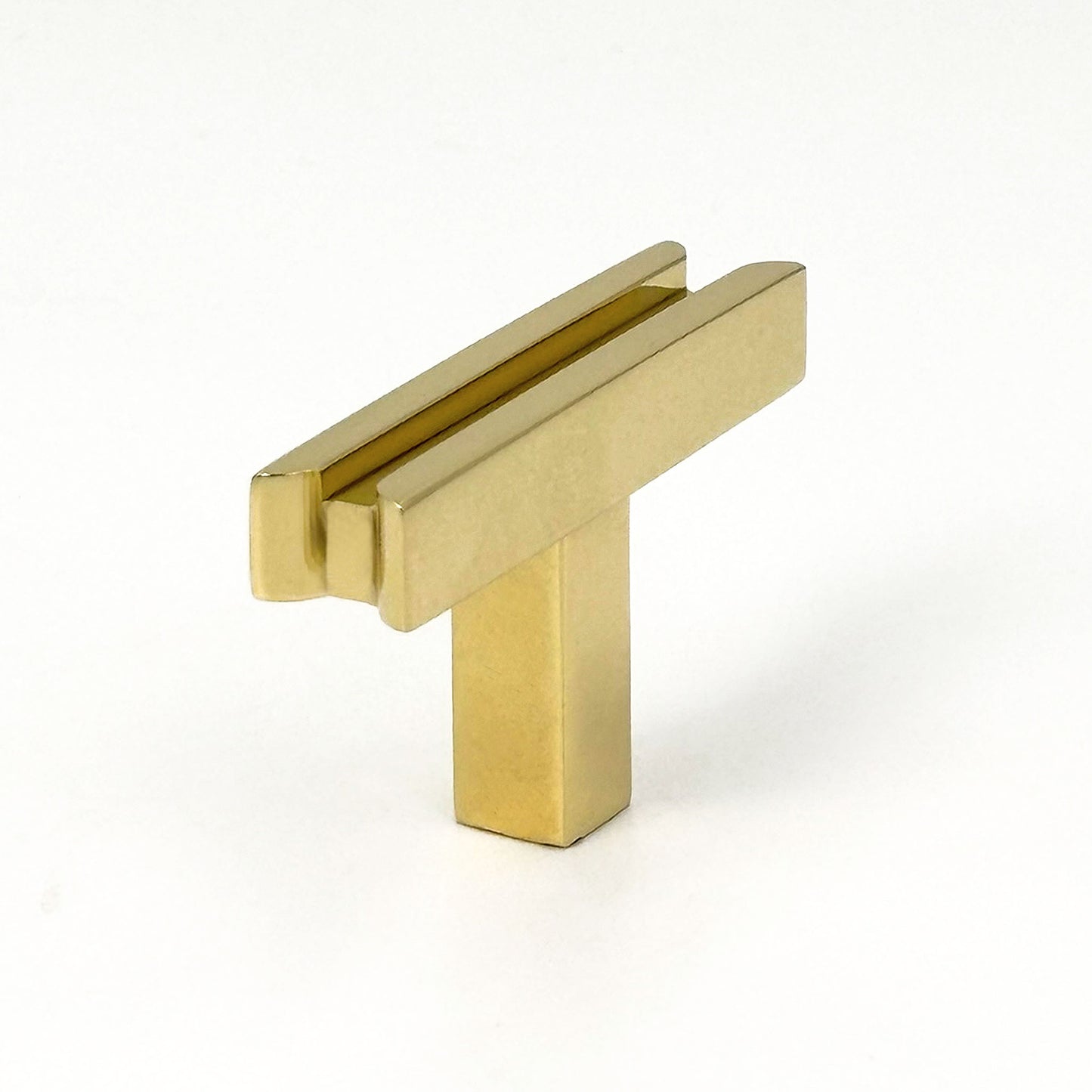 Angeled view of unlacquered brass cabinet T-pull handle on a white background