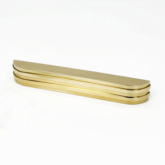 Angeled View of the ribbed brass Carrara Cup Appliance pull on a white 