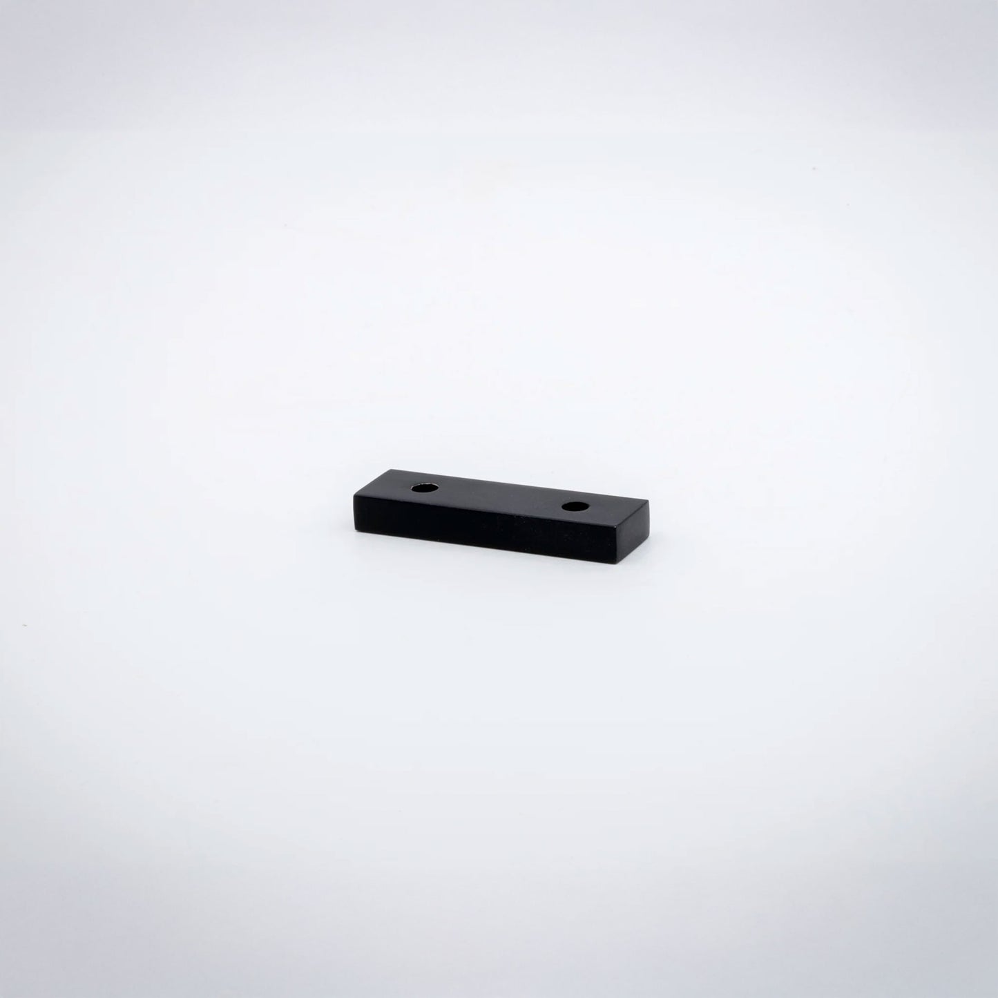 A small rectangular matte black  hardware piece with two pre-drilled holes, shown on a plain white background.