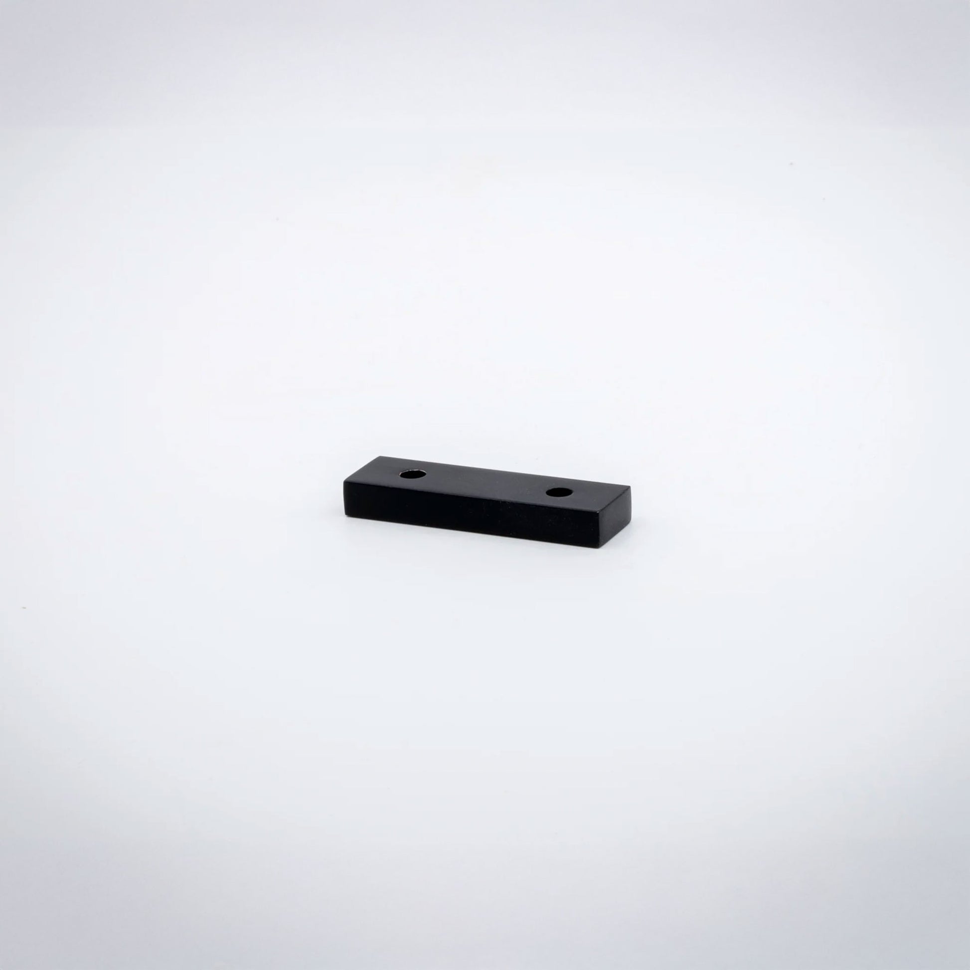 A small rectangular matte black  hardware piece with two pre-drilled holes, shown on a plain white background.