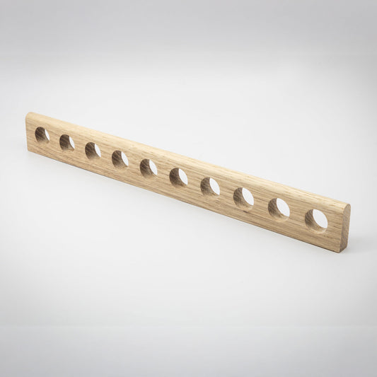 A light natural wood rectangular bar with ten evenly spaced circular holes, photographed on a clean light gray studio background.