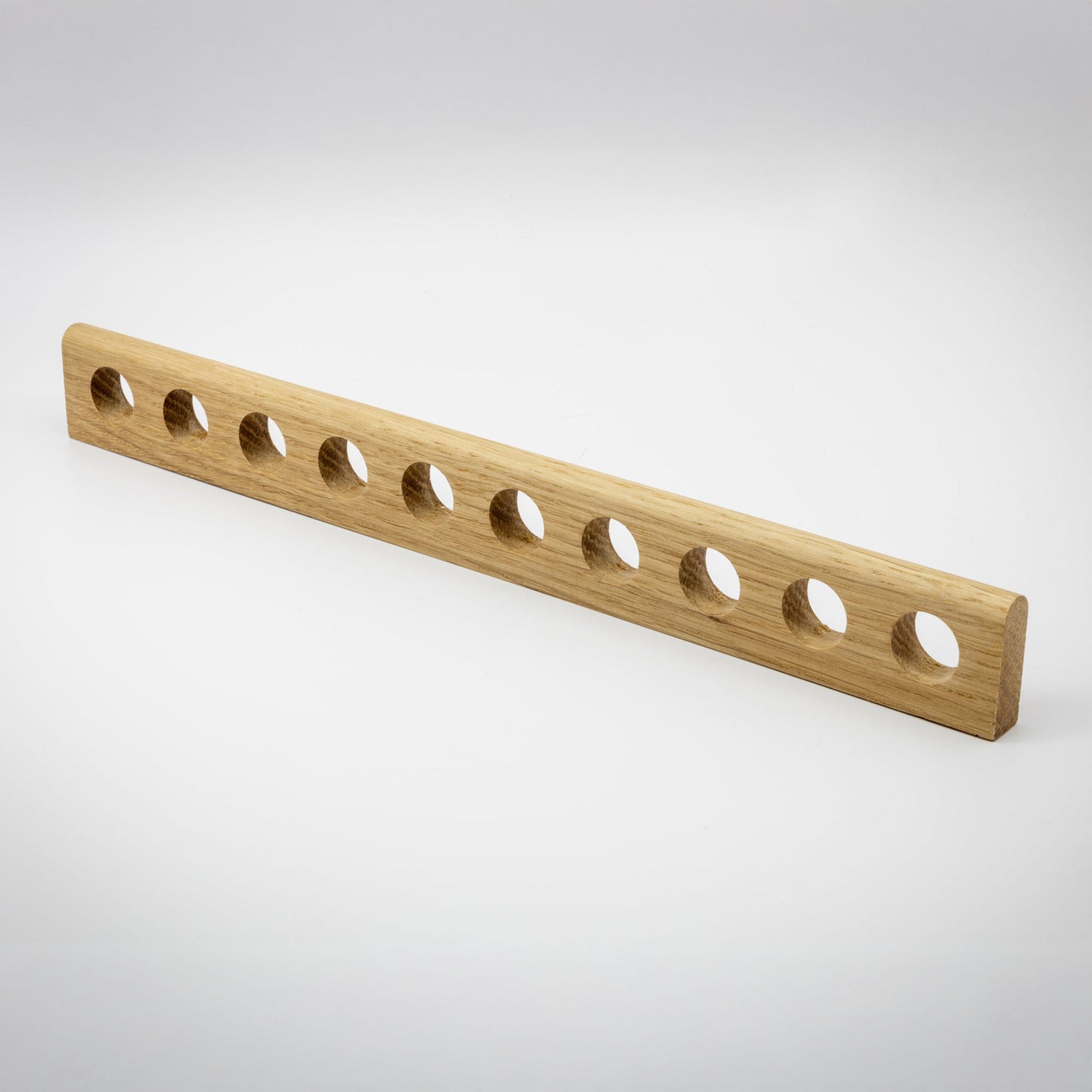A light natural wood rectangular bar with ten evenly spaced circular holes, shown on a clean light gray studio background.