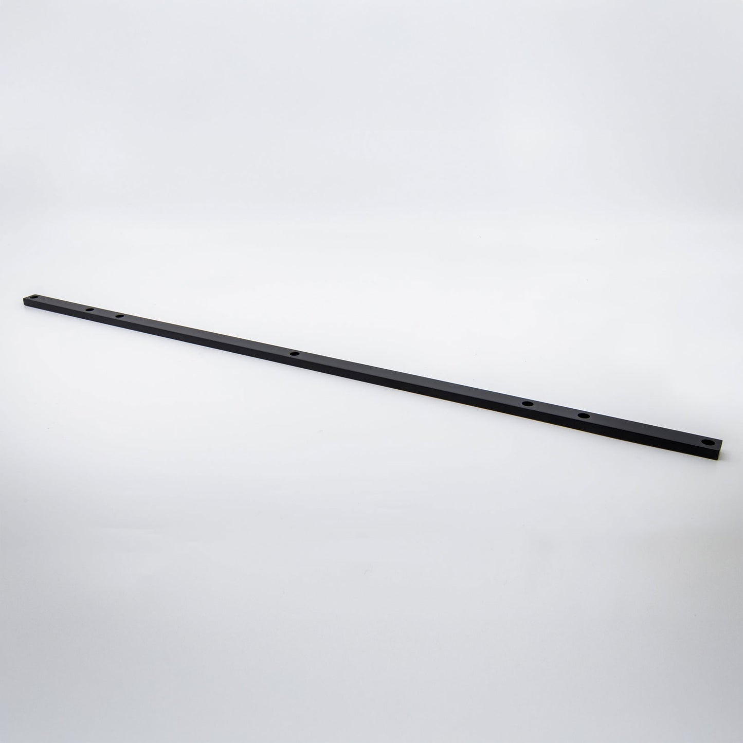 A long, thin black metal mounting bracket or hardware bar with pre-drilled holes, shown diagonally on a light gray studio background.