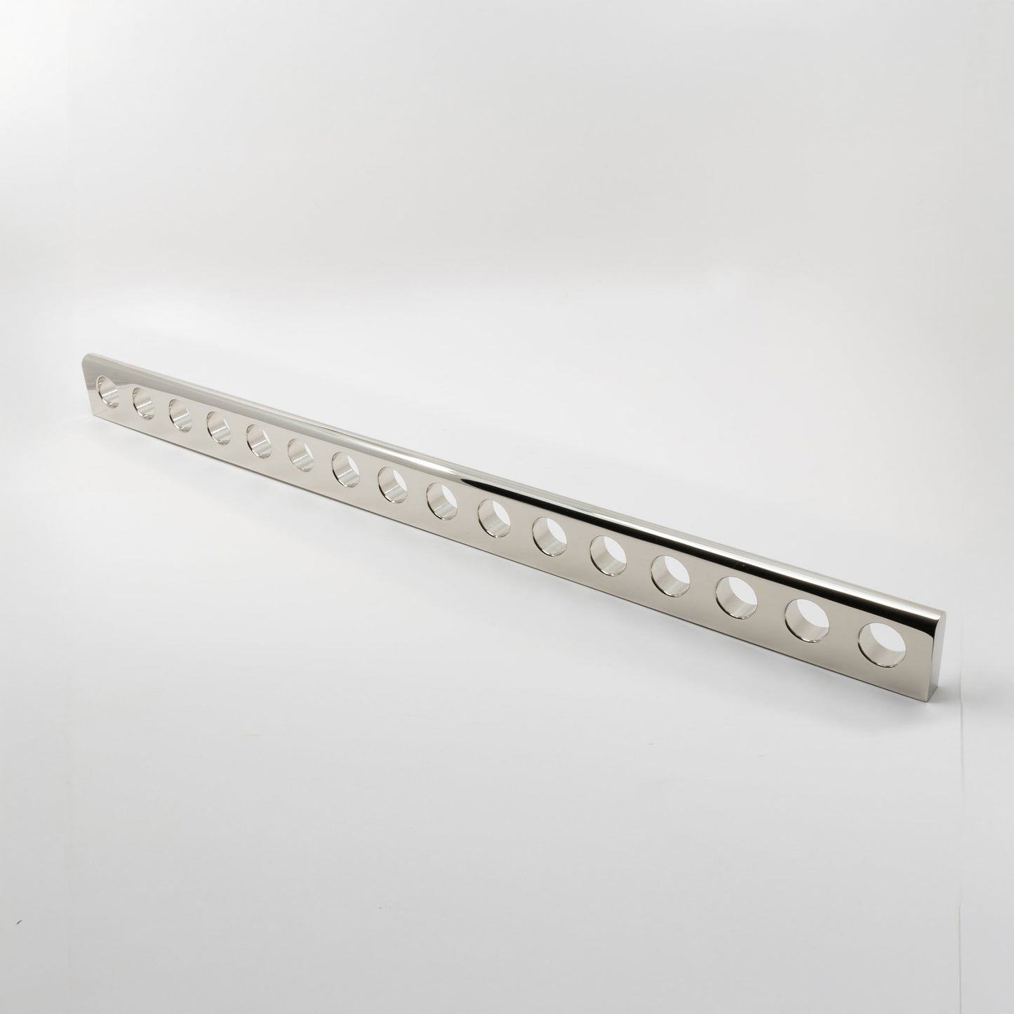 A long, narrow polished metal handle bar with a series of evenly spaced circular cutouts, photographed on a clean white studio background.