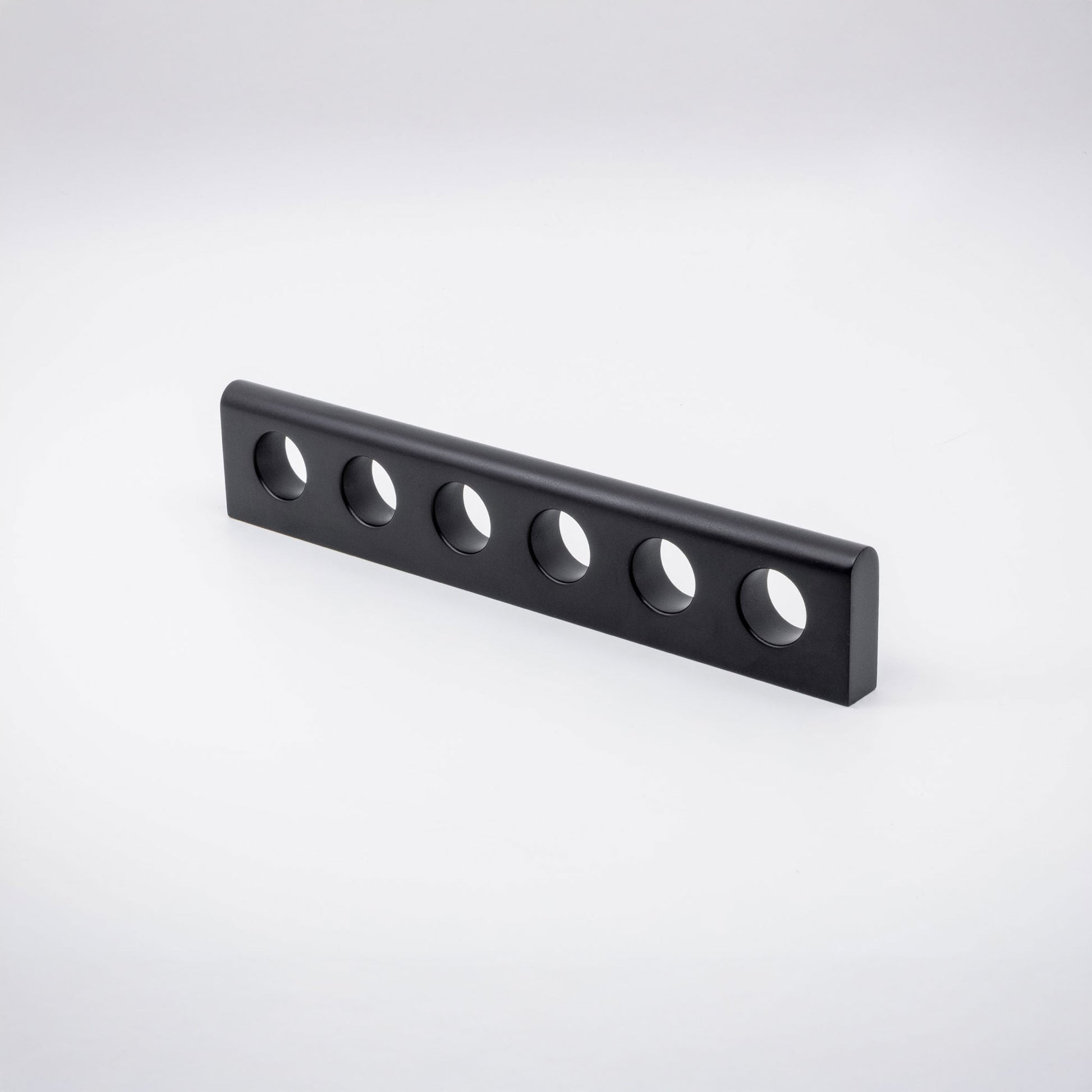 A black brass metal handle with six evenly spaced circular cutouts, shown on a clean white studio background.