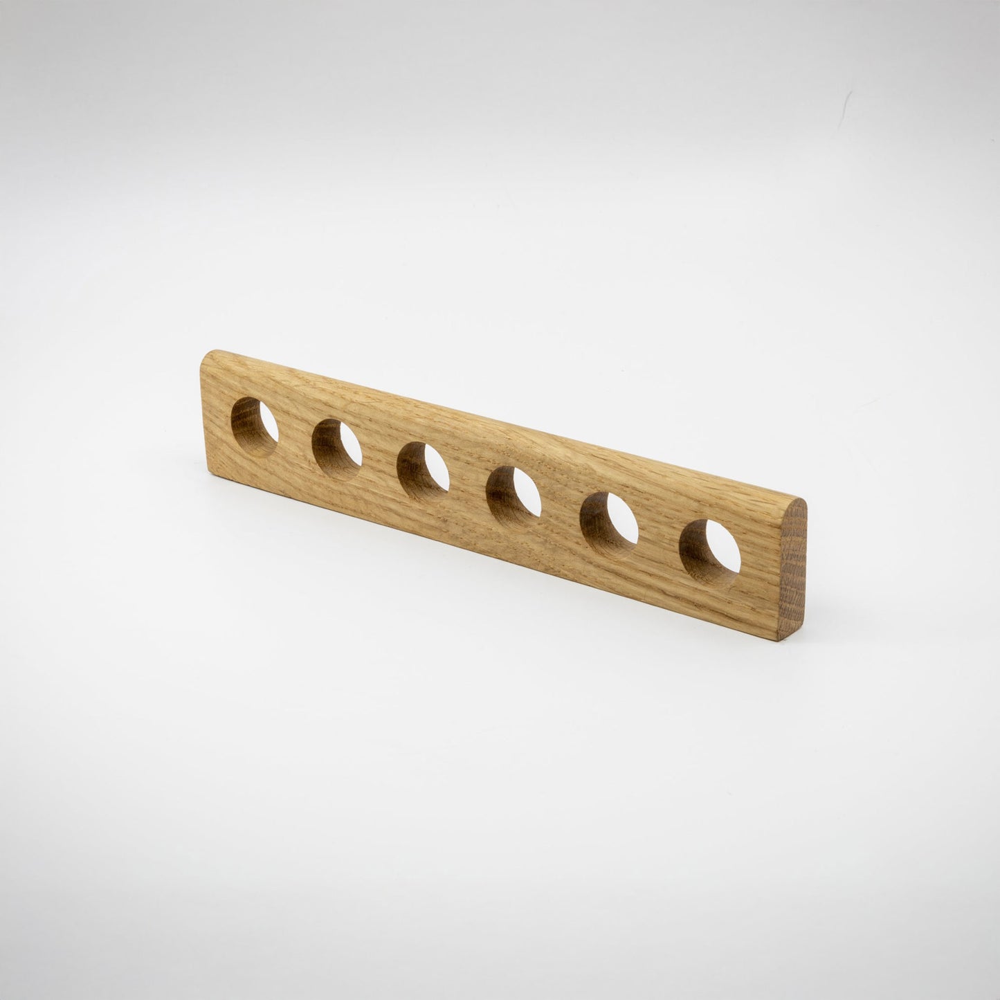 A long wooden oak hardware handle with six evenly spaced circular cutouts, shown on a clean white studio background.