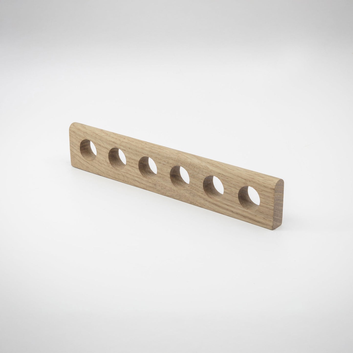 An oak-finished hardware handle with six evenly spaced circular cutouts, shown on a clean white studio background.
