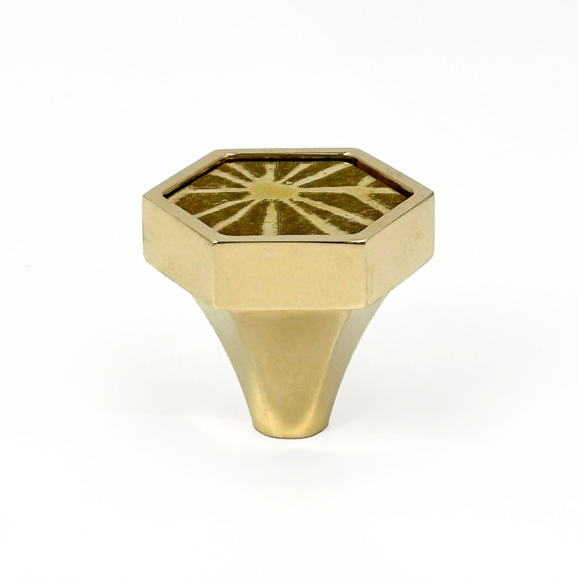 Hexagonal brass knob with etched sunburst design on a white background