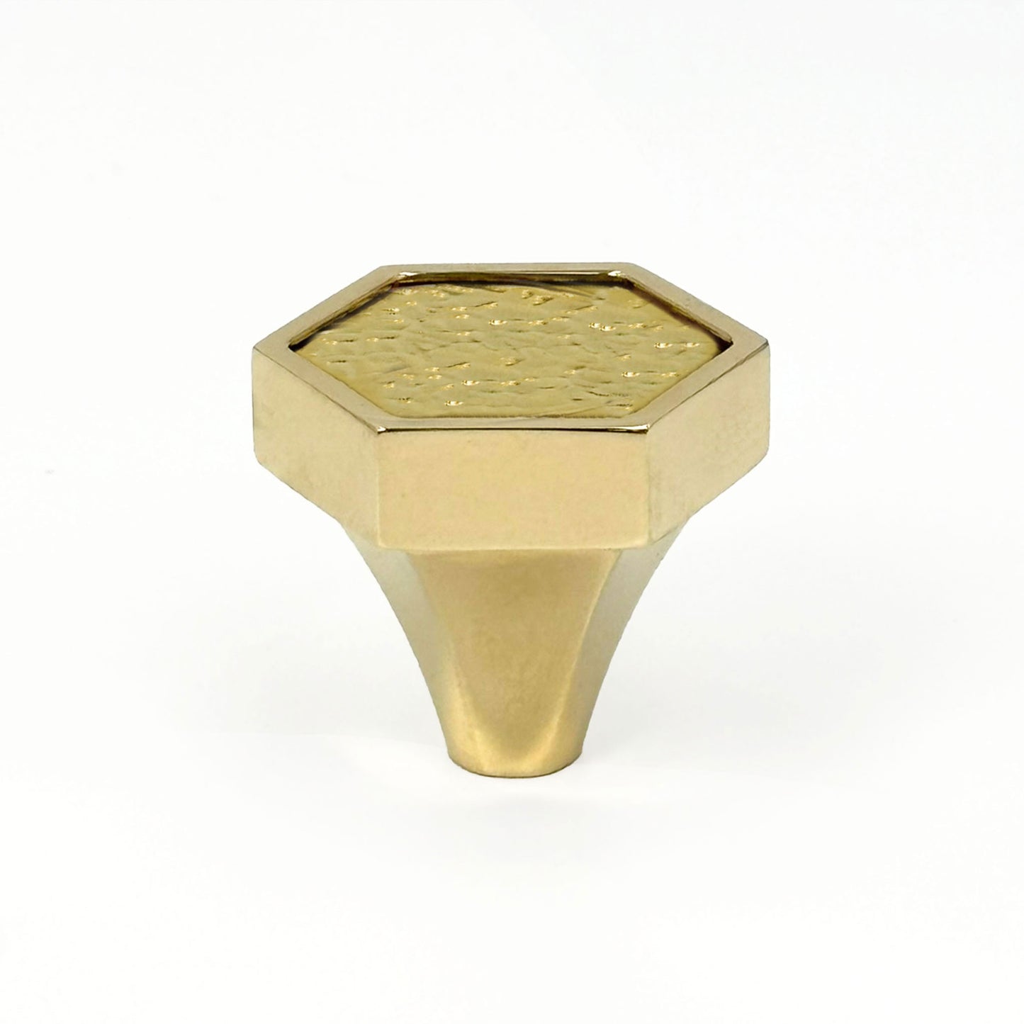 Brass Hex xhaped cabinet pull with surface texture on a white bacground