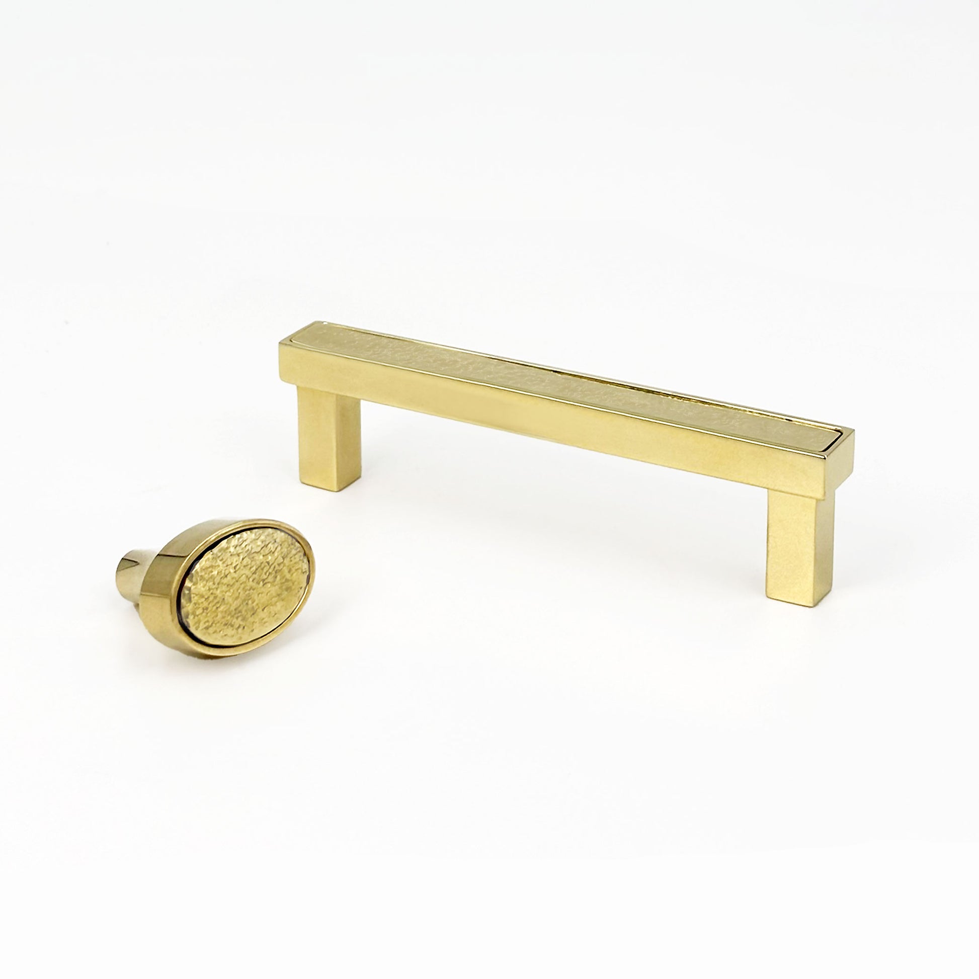 Brass hammered face cabinet pull and oval knob on a white background