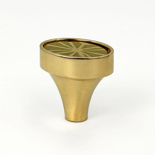 Brass colored oval knob with a sunburst pattern on a white background