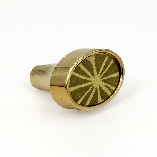 Brass colored oval knob with a sunburst pattern on a white background
