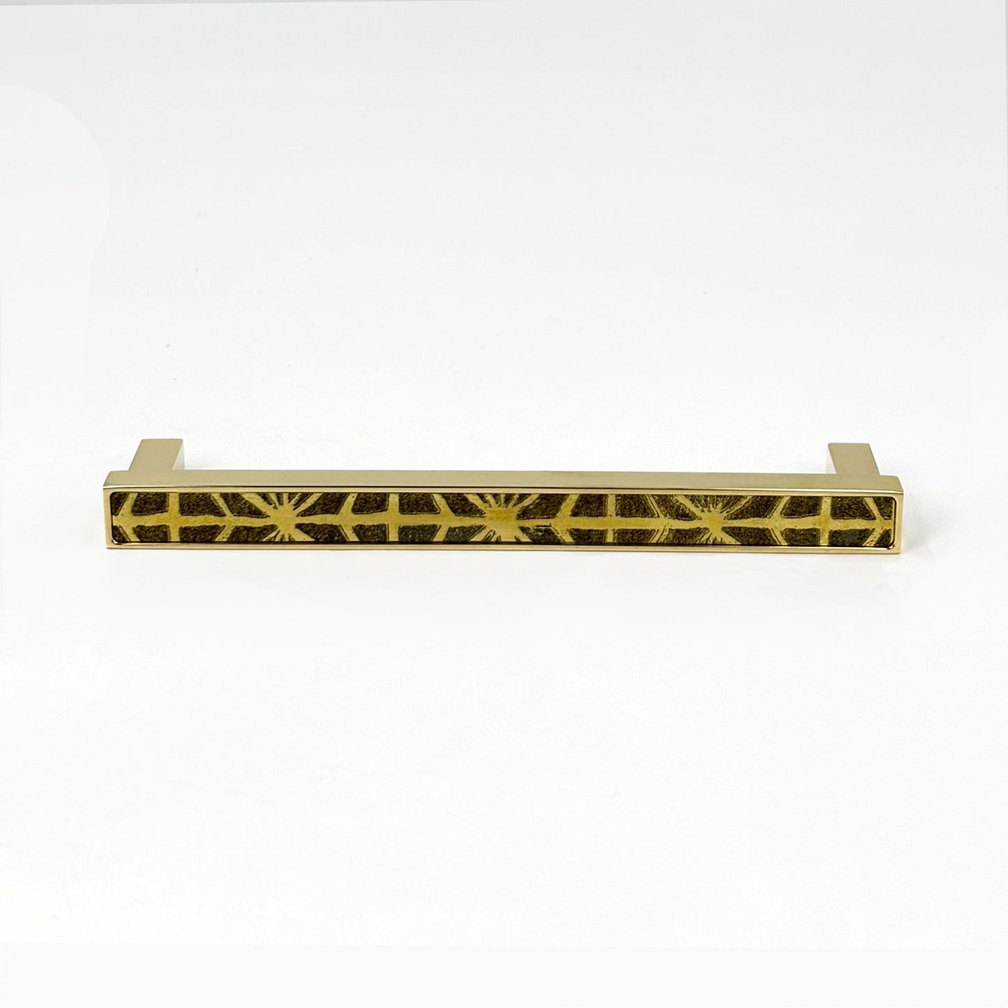 Brass cabinet pull with geometric pattern on a white background