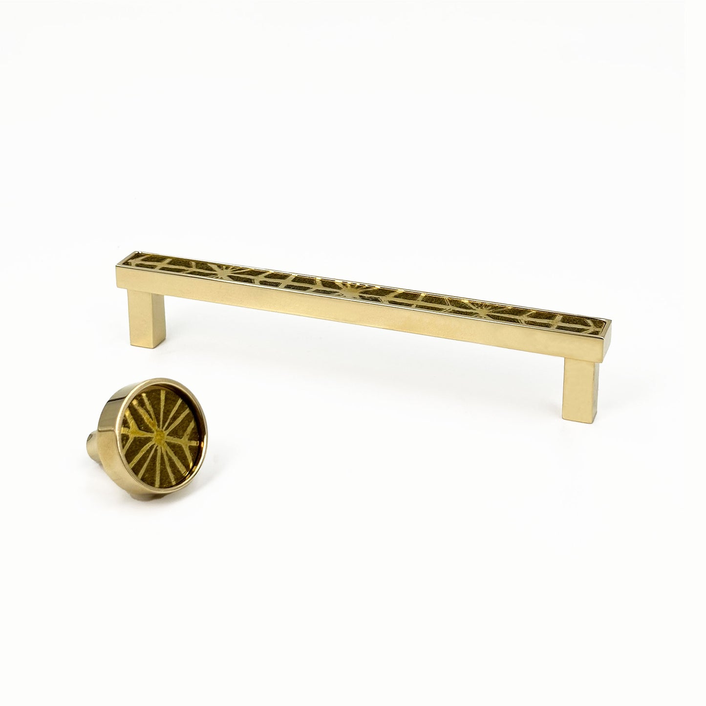 Brass patterned cabinet handle and knob on a white background