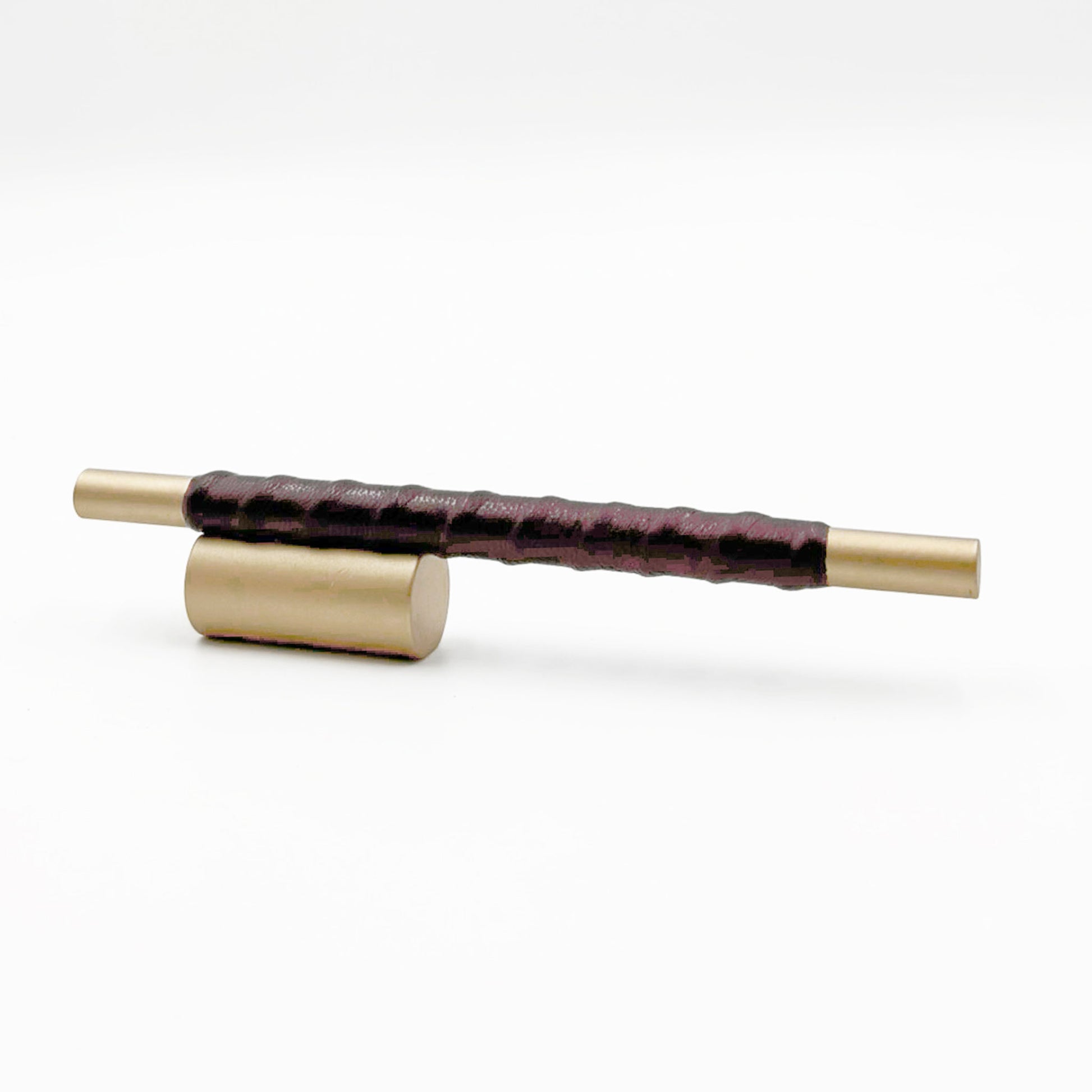 Satin Brass cylindrical cabinet pull with burgundy leather wraped handle on a white background