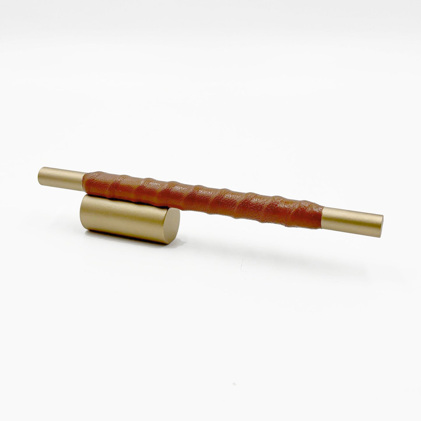 Satin Brass cylindrical cabinet pull with cognac leather wraped handle on a white background