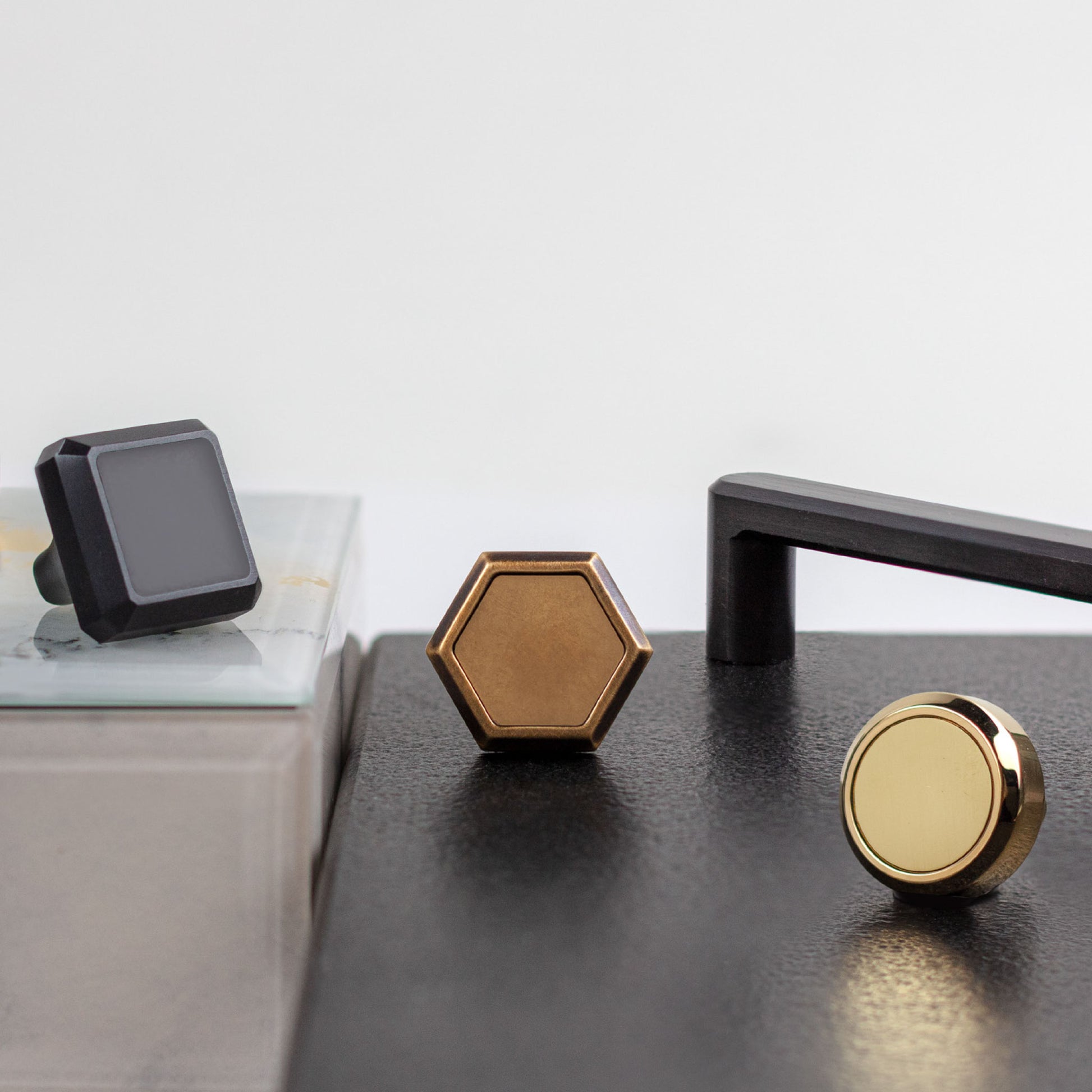 Set of metallic cabinet handles on a dark surface with a light gray background