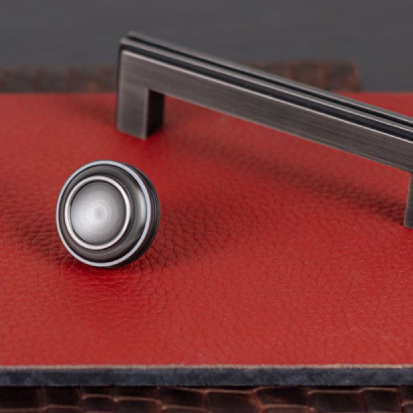 Close-up of a red leather surface with a metal handle and cabinet knob