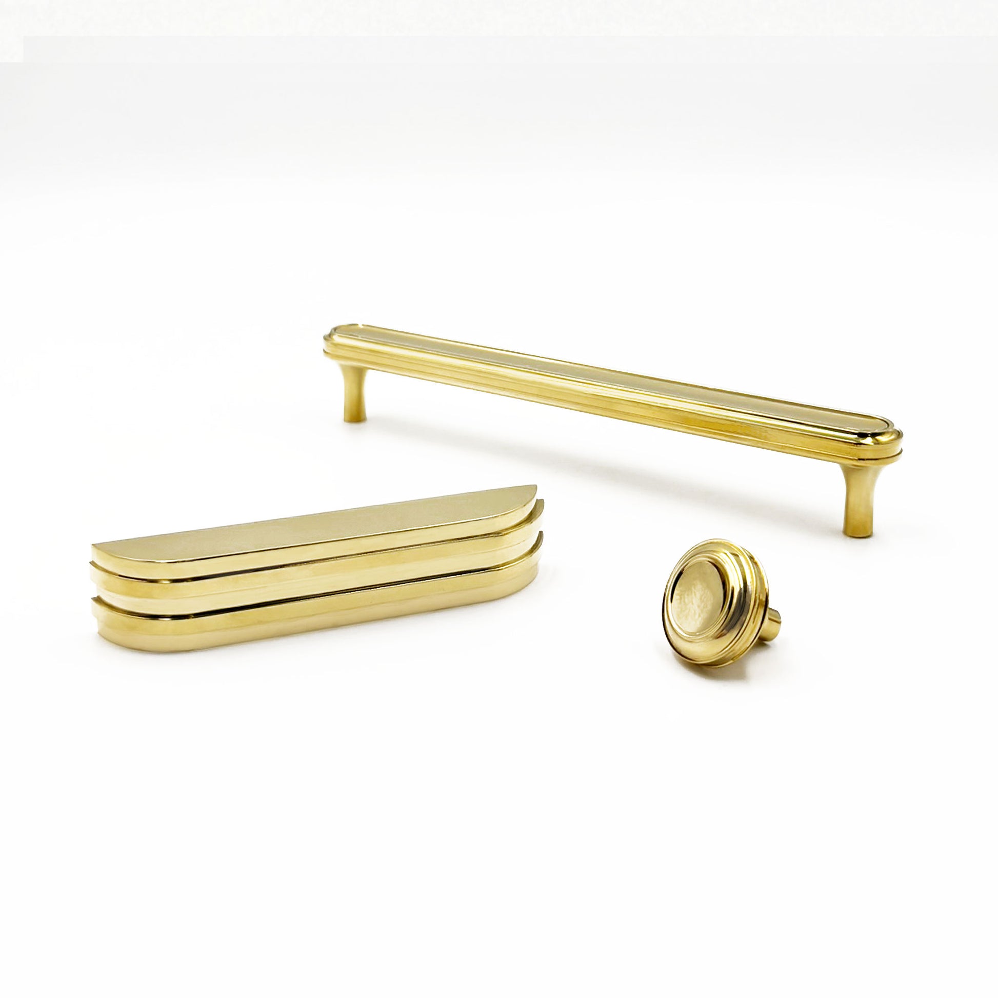 a cup pull, knob and long brass pull on a white background