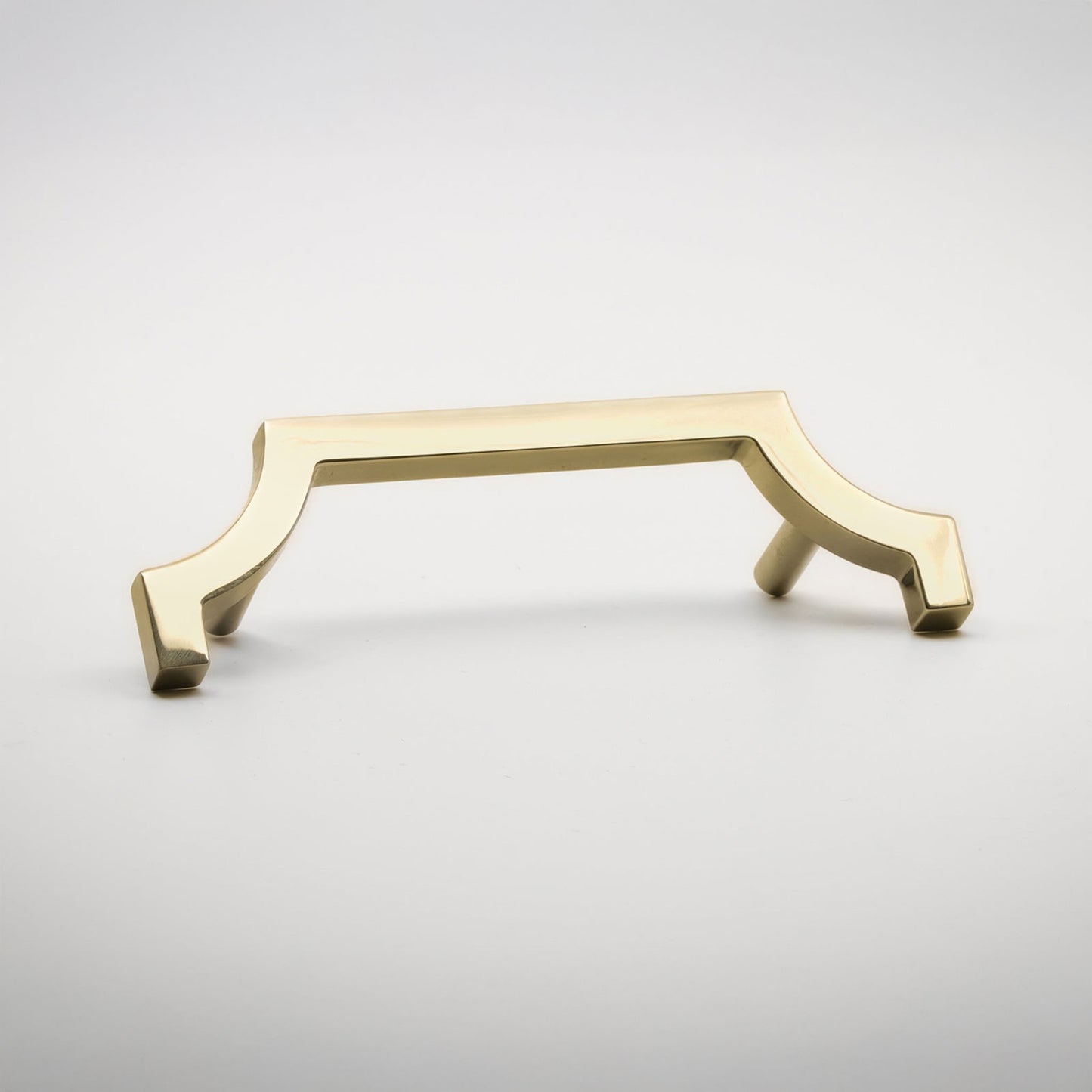 A modern bar pull handle with a curved, geometric design in a brushed brass or gold finish, shown on a light gray background.