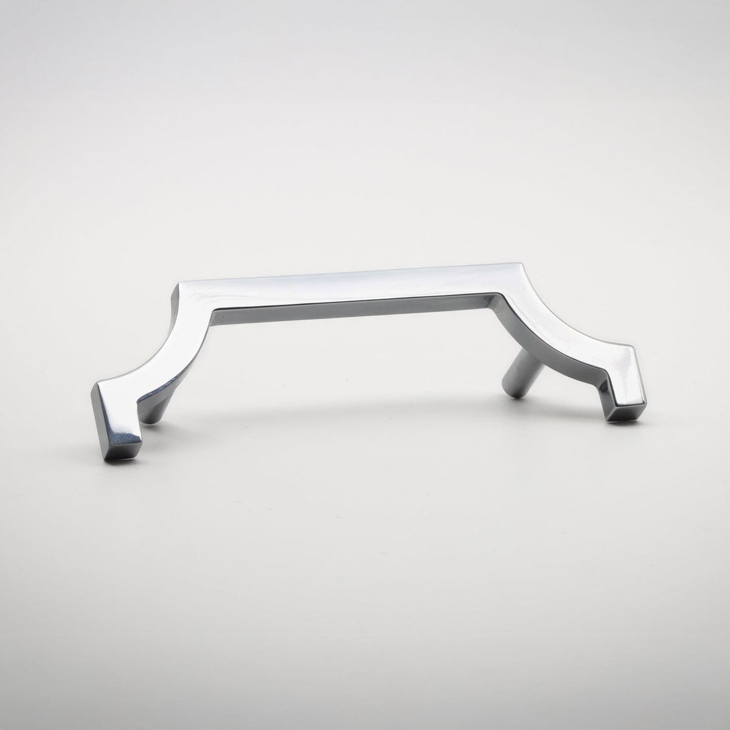 A modern polished chrome cabinet pull handle with a curved, geometric design, shown on a neutral light gray background.