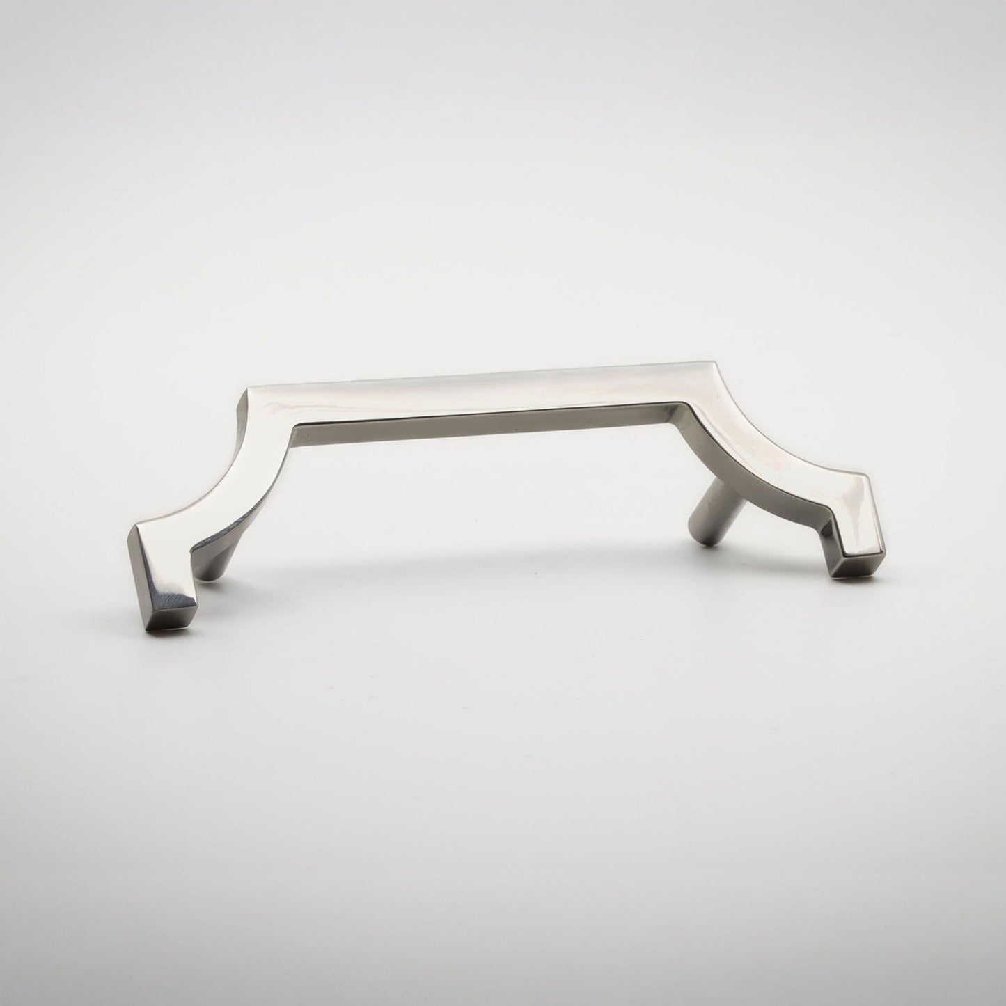 A nickel-finished metal hardware pull with a decorative half quatrefoil-style frame and flat side pegs, shown on a light gray background.