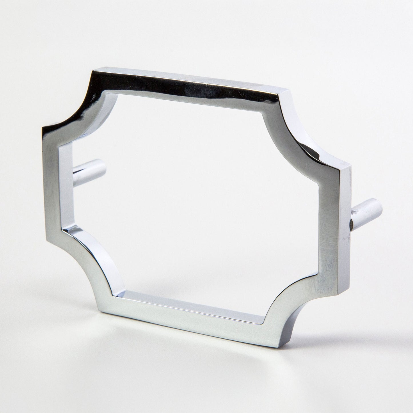A chrome-finished metal hardware pull with a decorative quatrefoil-style frame and flat side pegs, shown on a light gray background.