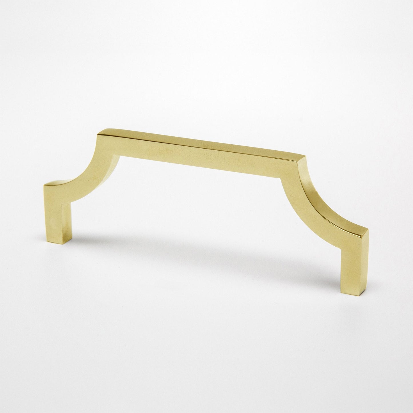 A polished unlaquered brass cabinet pull handle with a curved corner design on a clean white background.