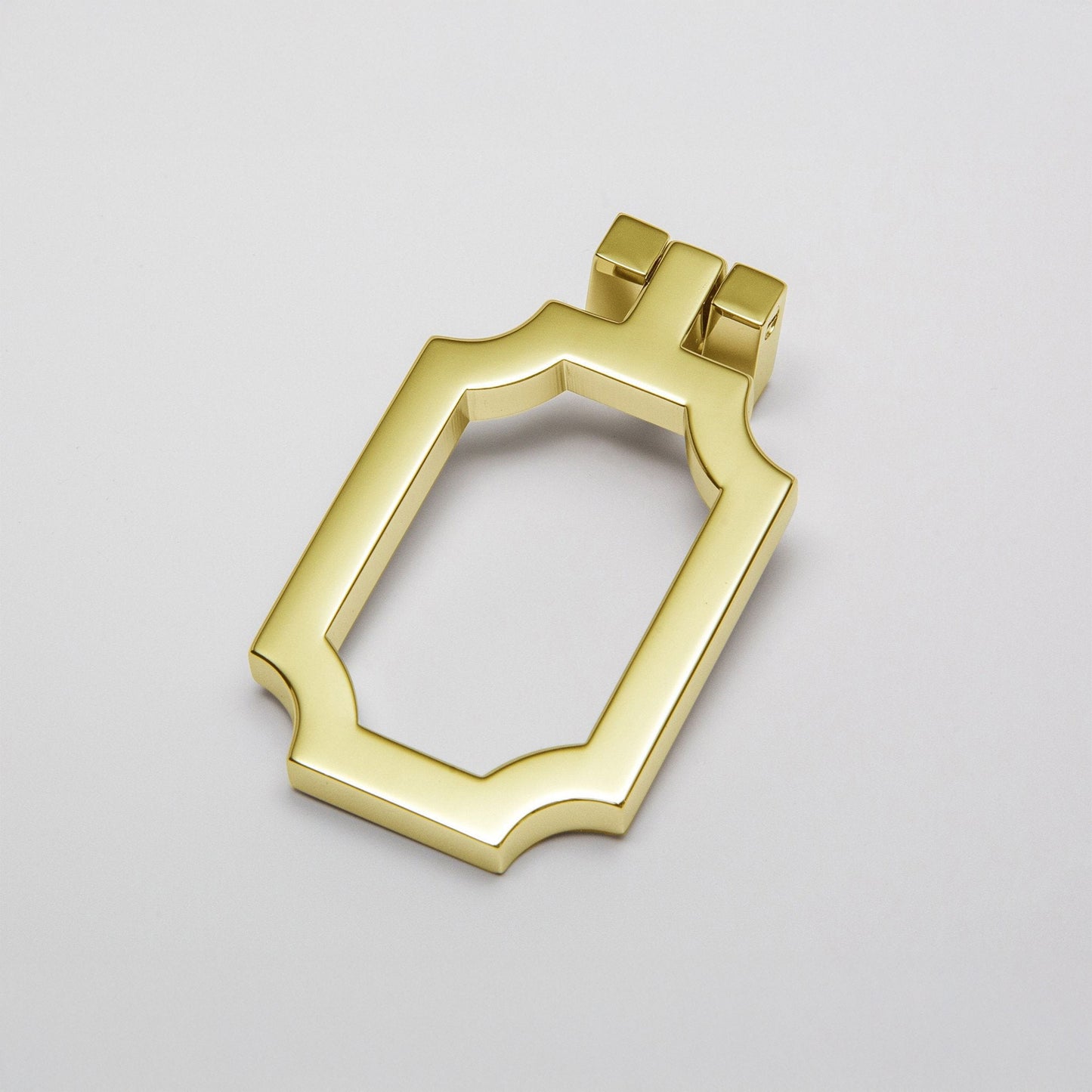 A small curved corners cabinet pull finished in a polished unlaquered brass, shown on a clean light gray background.
