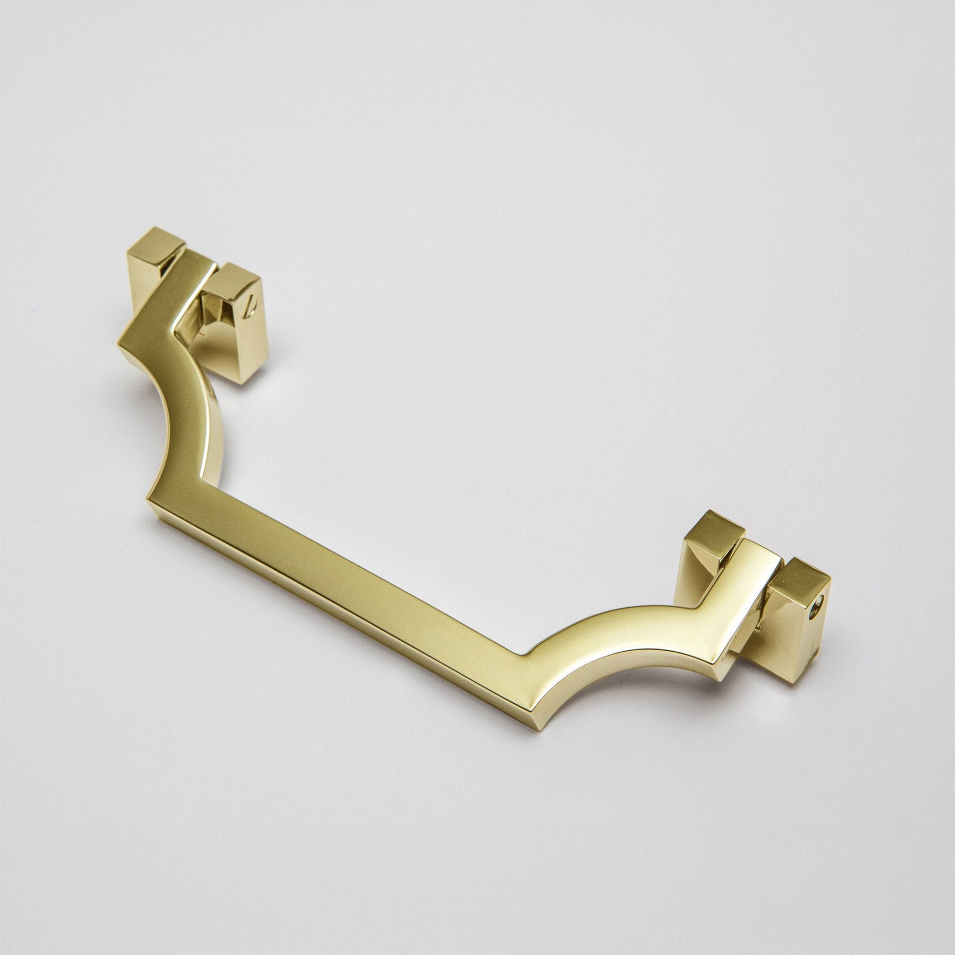 A modern curved bar handle drop pull in an unlaquered brass finish, shown on a light gray background.