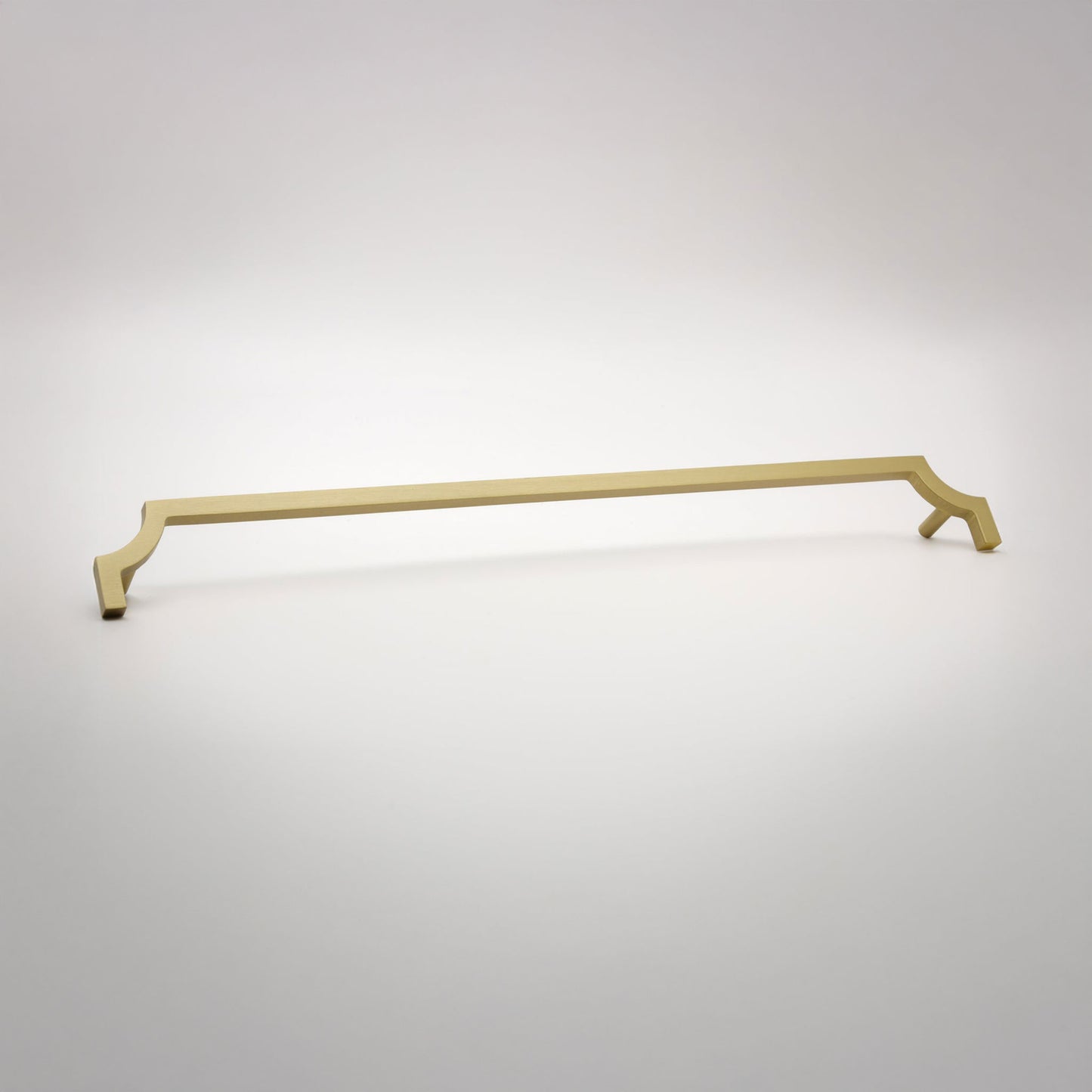 A long, slender cabinet pull in a satin brass finish shown against a neutral background.