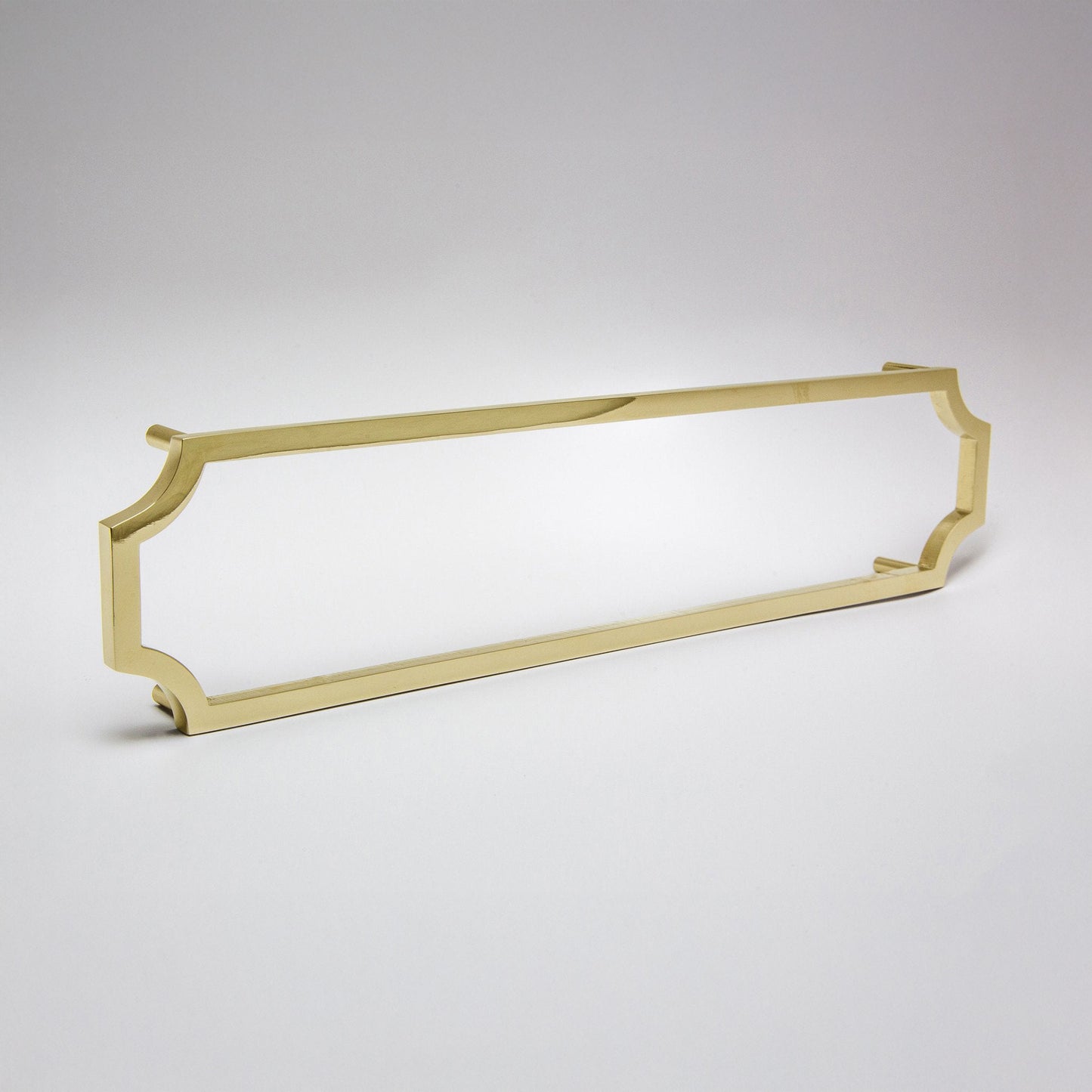 A long polished unlaquered brass cabinet pull with curved ends, shown on a light gray gradient background.