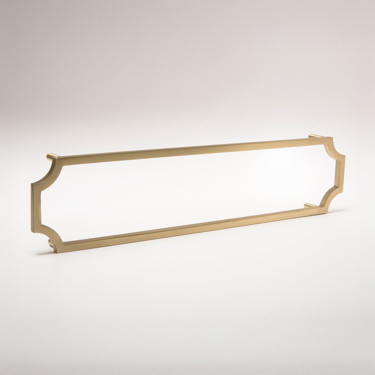 A long polished satin brass cabinet pull with curved ends, shown on a light gray gradient background.