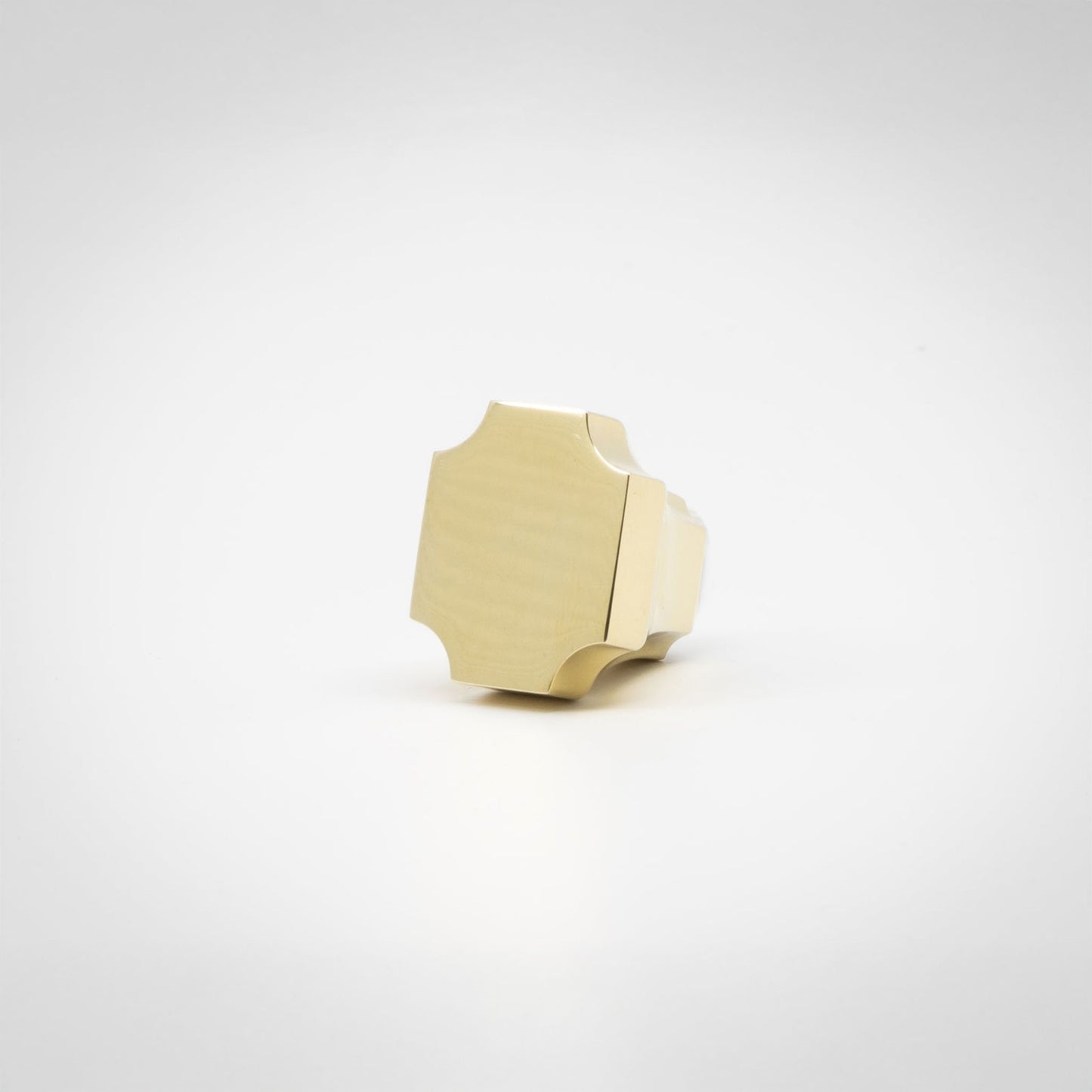 A small brass hardware knob with a geometric, faceted shape, photographed on a seamless white background.