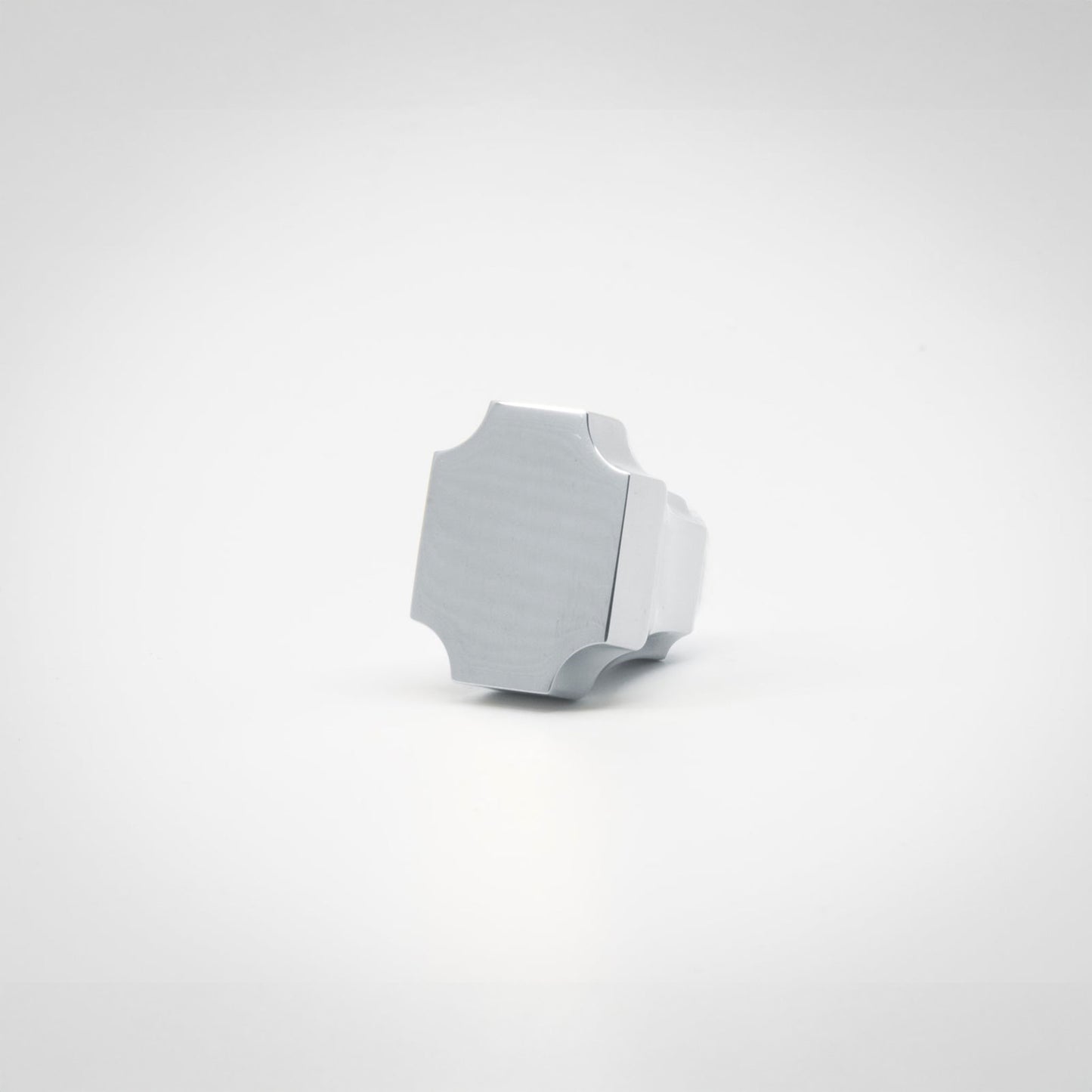 A small polished chrome hardware knob with a geometric, faceted shape, photographed on a seamless white background.