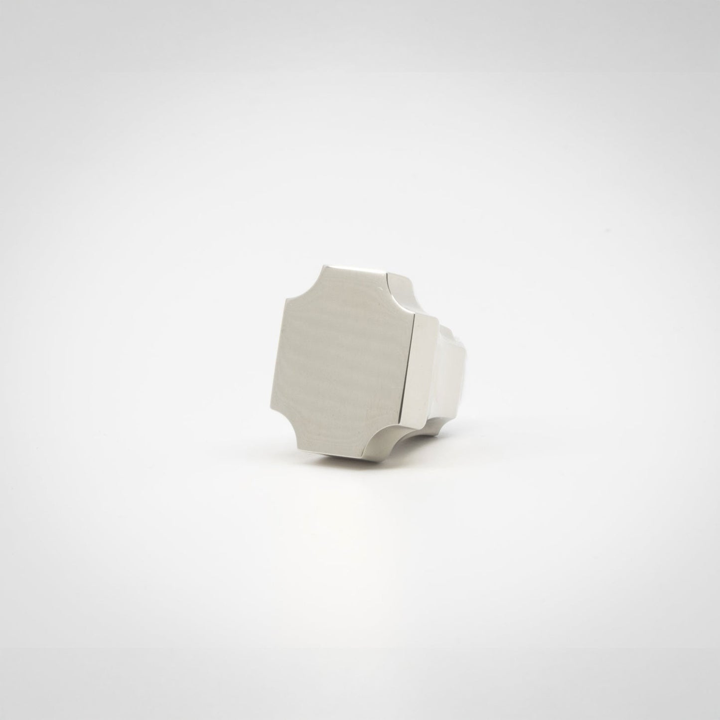 A small polished nickel knob with a geometric, faceted shape, photographed on a seamless white background.