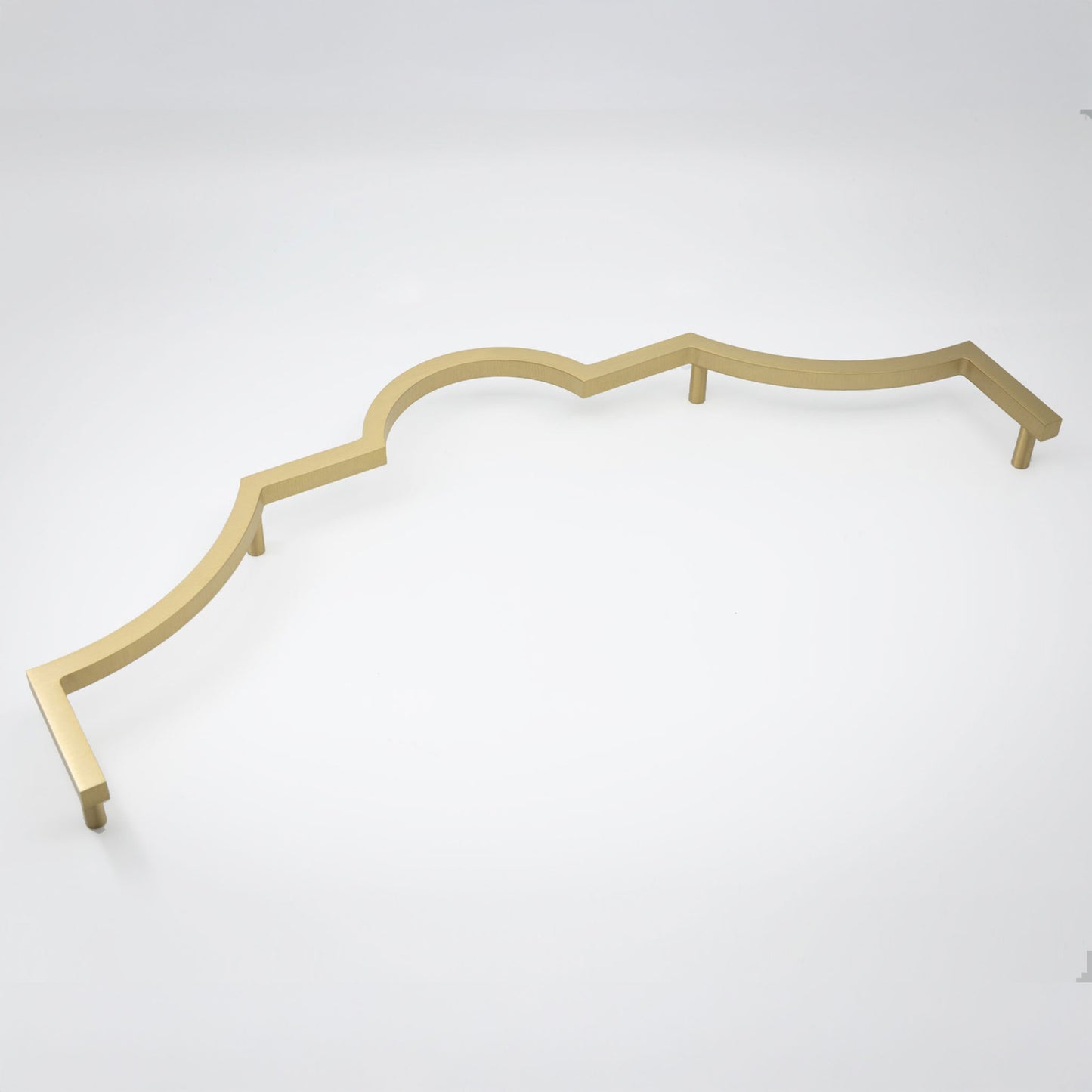 A long decorative cabinet pull handle with a wavy scalloped edge, in a satin brass shown on a clean light gray studio background.